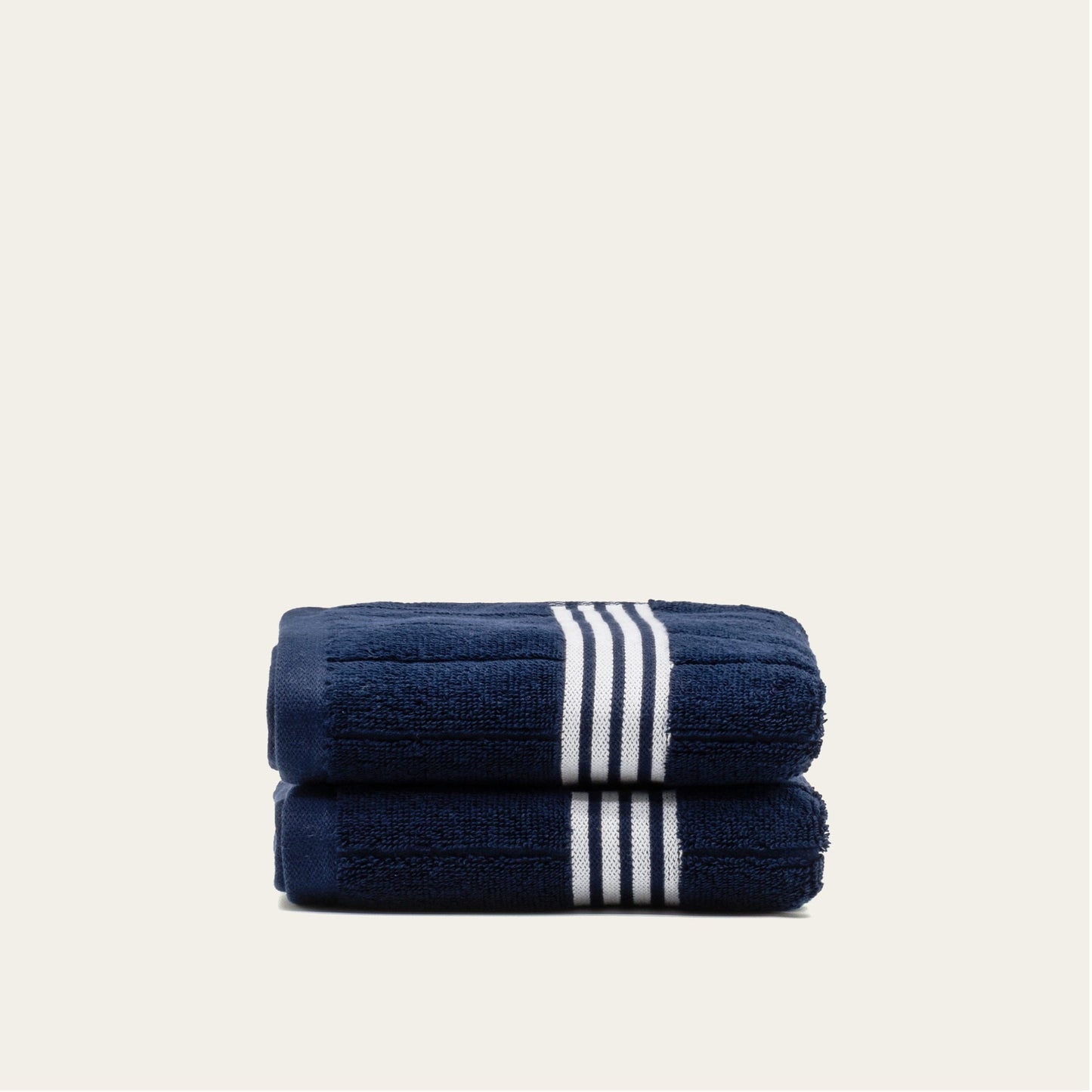 Navy cotton towels set with white striped bands, two folded towels showing vertical stripe bands.