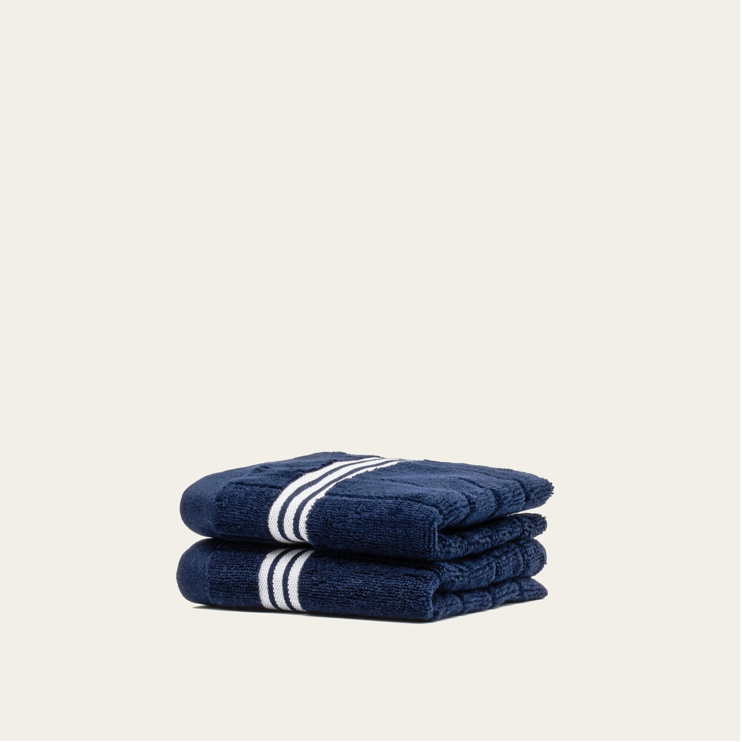 Navy cotton towels set with white striped bands, two folded towels stacked and partially wrapped.
