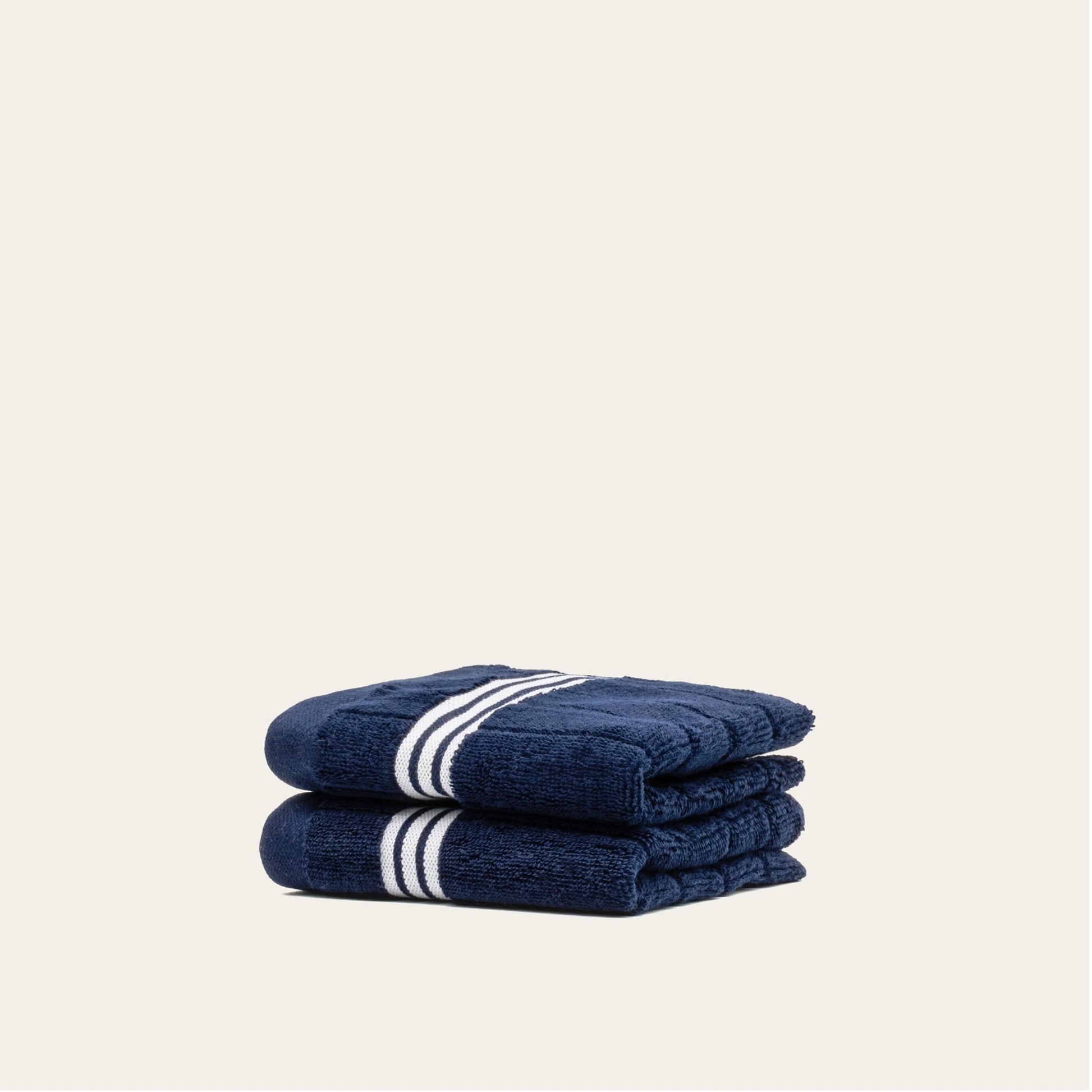 Navy cotton towels set with white striped bands, two folded towels stacked and partially wrapped.