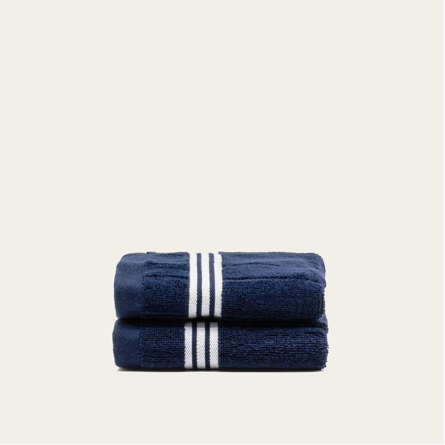 Navy cotton towels set with white triple stripe bands, stacked and folded.