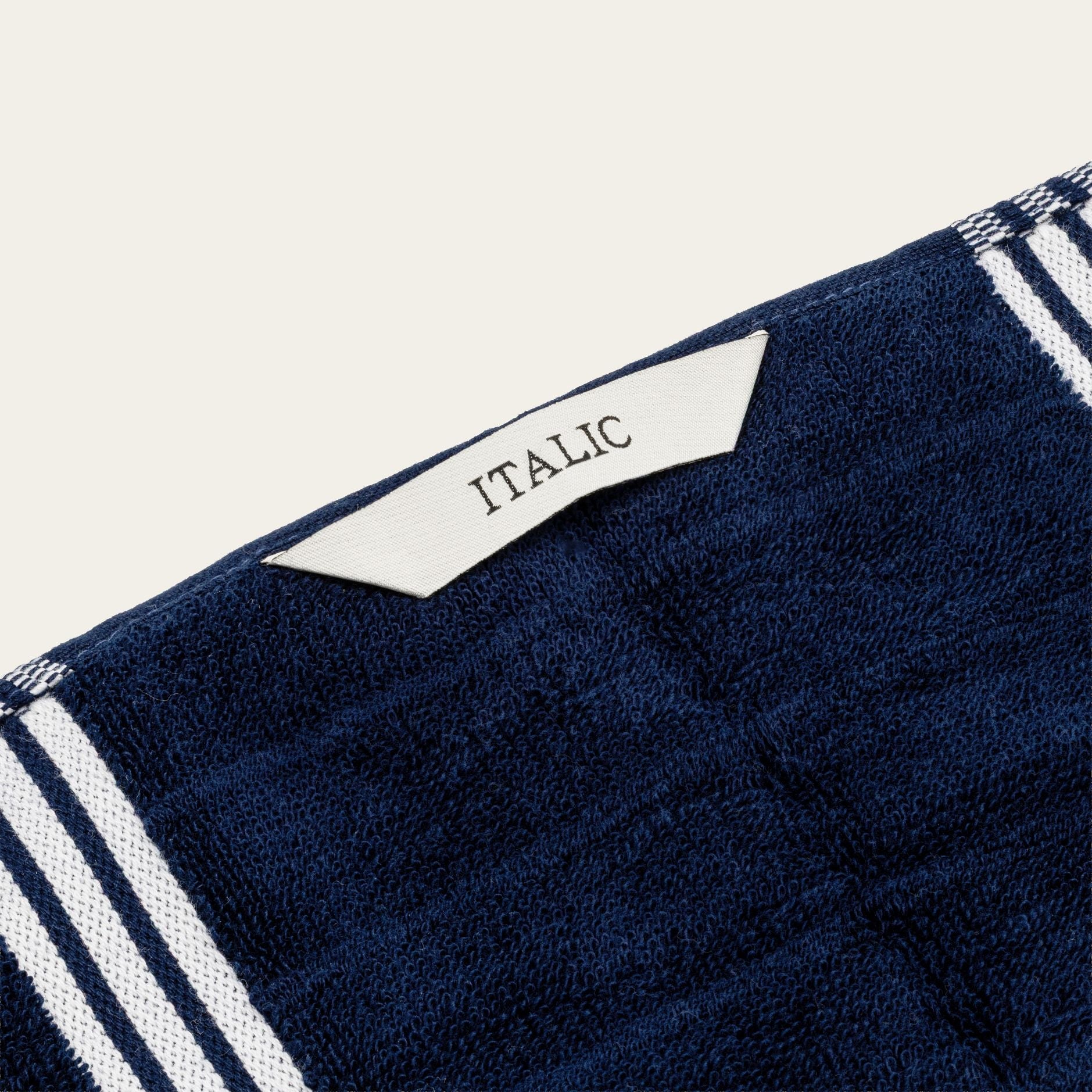 Navy cotton towel corner with white stripe trim and small woven label reading "ITALIA".