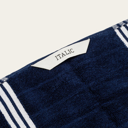 Navy cotton towel corner with white stripe trim and small woven label reading "ITALIA".