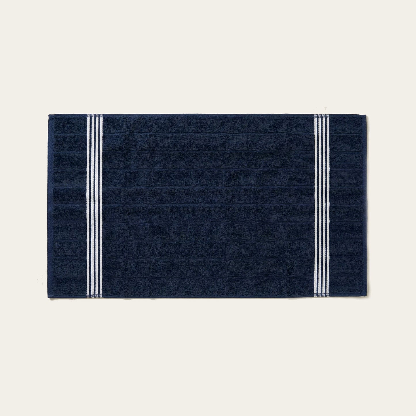 Navy cotton bath towel with white triple stripe bands on the sides.