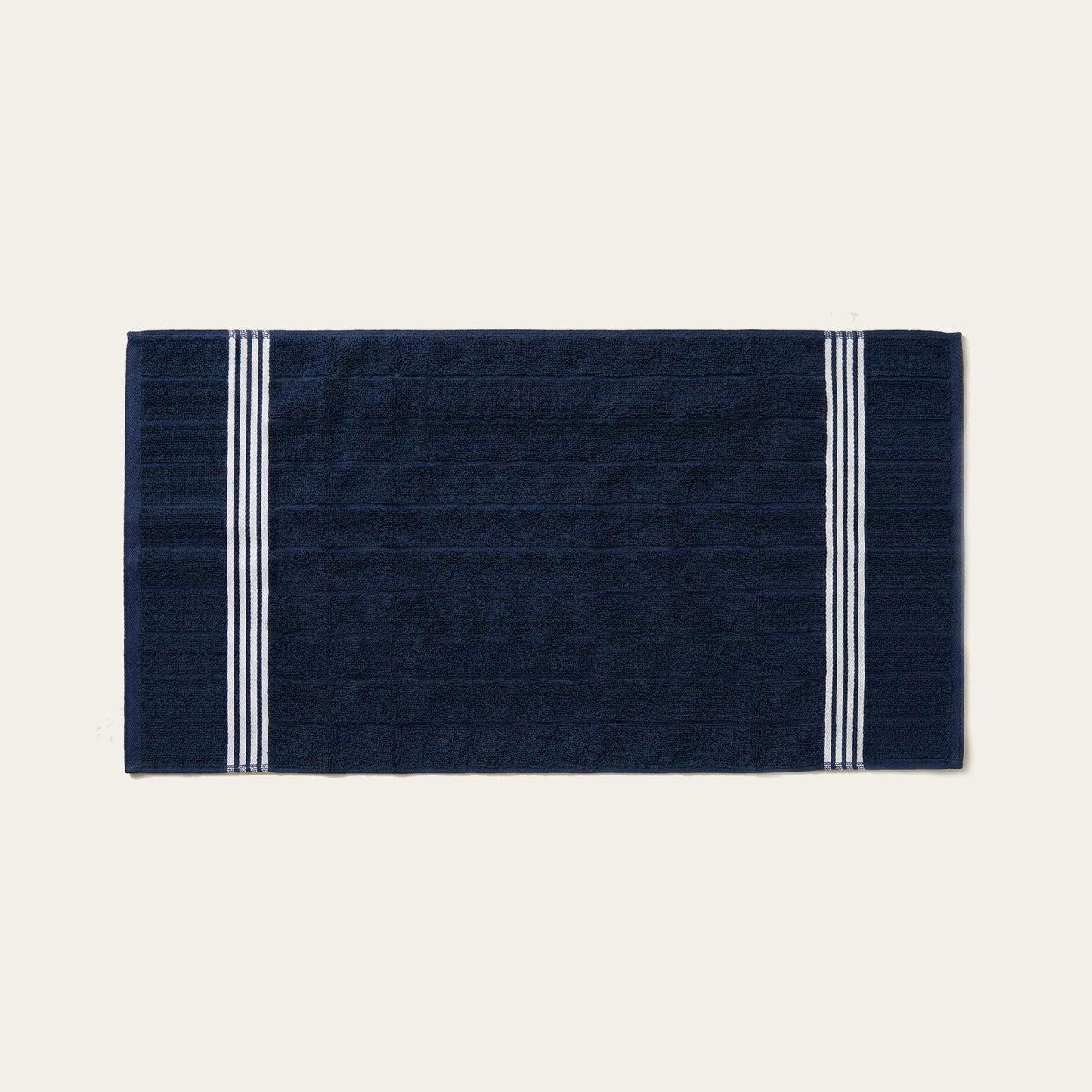 Navy cotton towel with white triple stripe bands along the edges, folded flat.