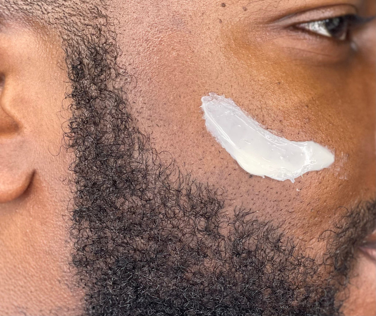Face moisturizer applied on cheek with facial hair, close-up skin texture