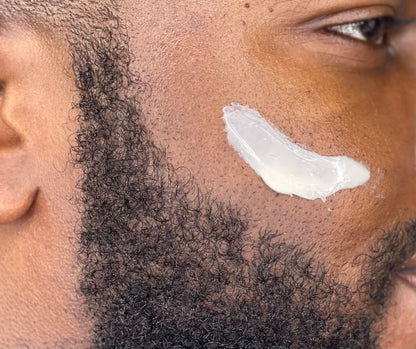 Face moisturizer applied on cheek with facial hair, close-up skin texture
