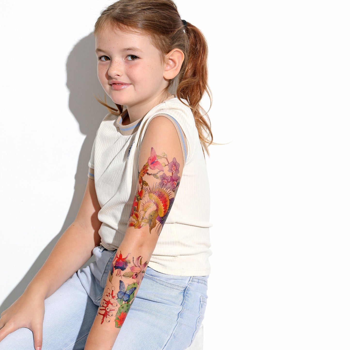 Child wearing temporary tattoo sleeve on upper arm with colorful floral and rose art