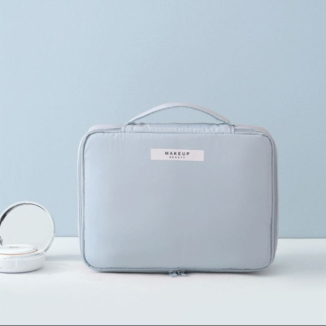 Cosmetic pouch pale blue, zip-top with front label and curved handle loop.
