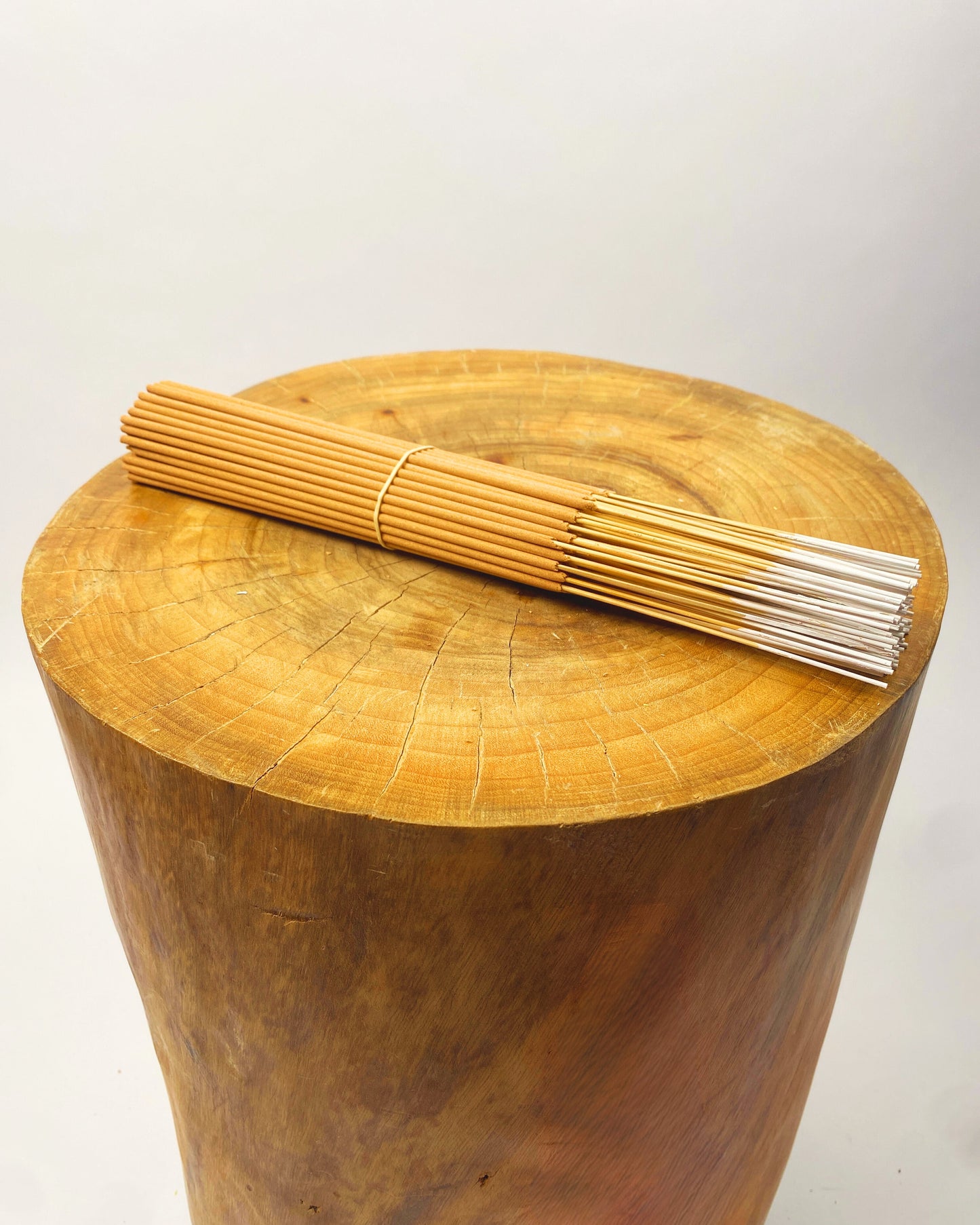 Incense stick bundle with white sticks on a round wooden tray