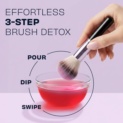 Makeup brush held above a bowl of rose-pink brush cleaner
