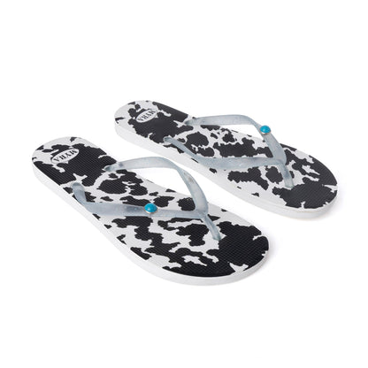 Pair of cowhide slippers with black-and-white cow print straps, light blue thong