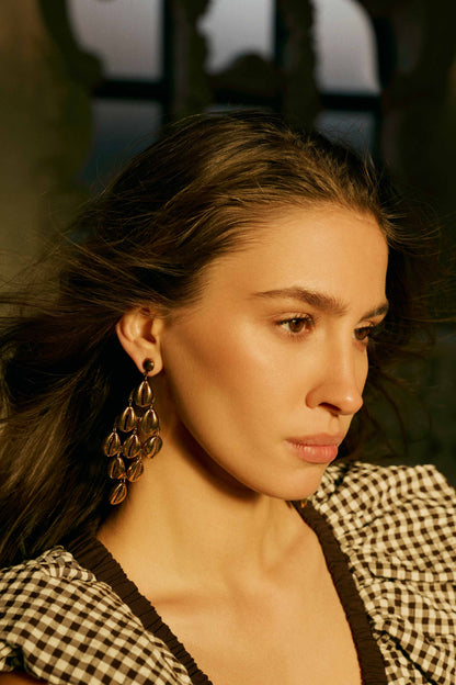 Gold shell-style drop earrings on model, long leaf charms hanging