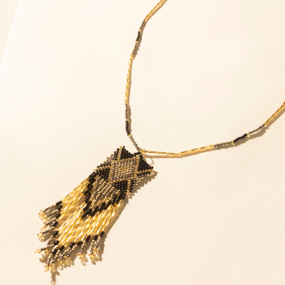 Beaded pendant necklace with black and gold tassel drop on a chain