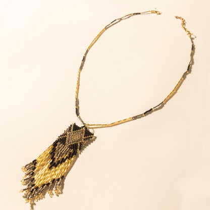 Beaded necklace with gold chain and dark brown star-like pendant with tassels