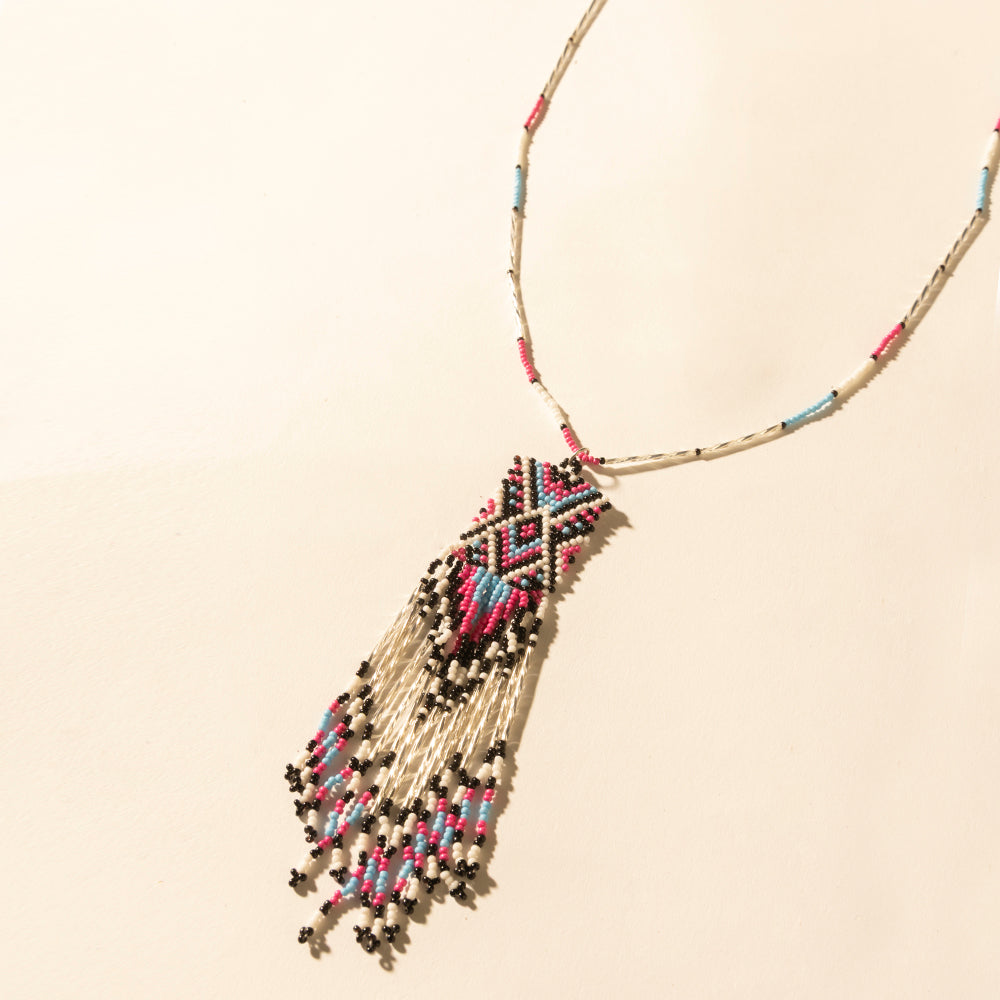 Turquoise beaded necklace with coral, black, and white fringe tassel detail