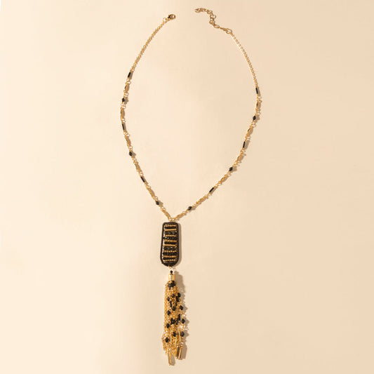 Burnished tan pendant necklace with black-gold charm and tassel drop