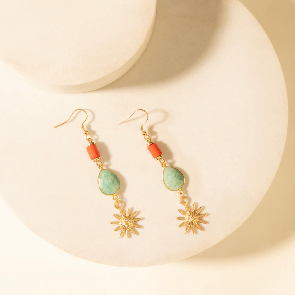 Gold-tone drop earrings with green teardrop stones, orange beads, and gold sunburst dangles.