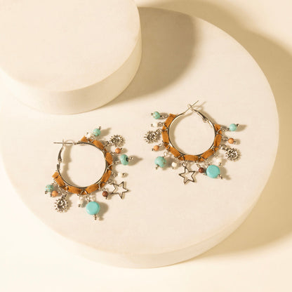 Gold-tone hoop earrings with turquoise beads and star charms, dangling sparkly discs.