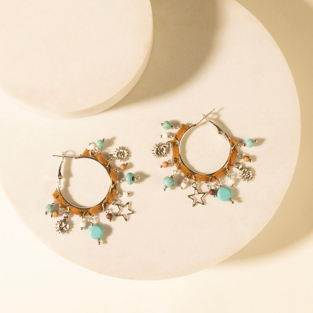 Gold-tone hoop earrings with turquoise beads, star charm, and dangling flower-like charms.
