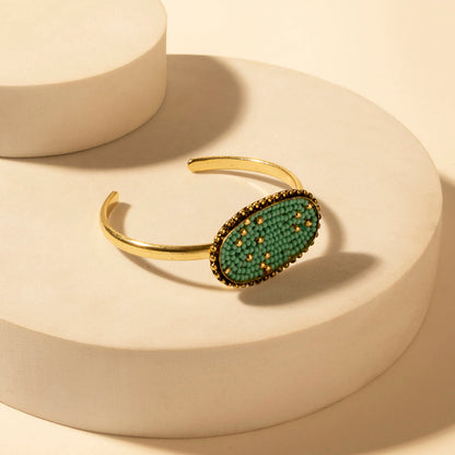 Gold tone oval cuff bracelet with turquoise beaded center