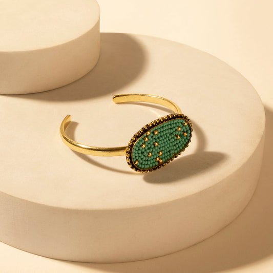 Gold tone oval cuff bracelet with turquoise beaded center