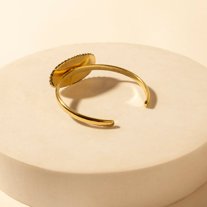 Gold tone open cuff bracelet with smooth band and rounded ends