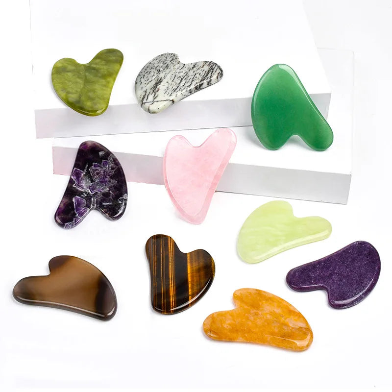 Facial gua sha stone set, assorted heart-shaped tools on white display in purple and green tones