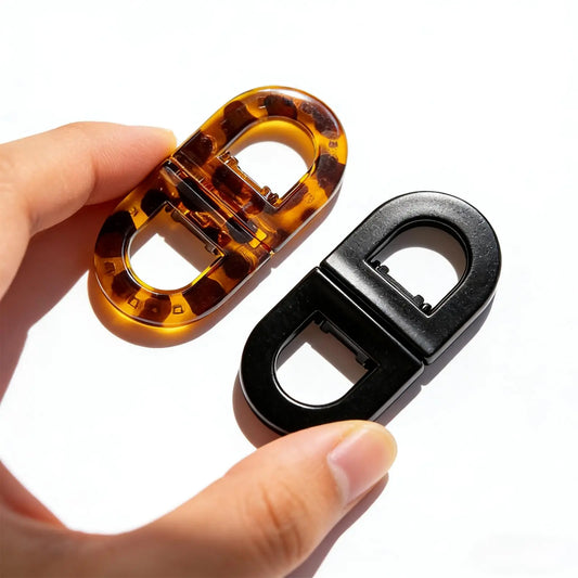 Magnetic hair clips in tortoise and black, shown held in hand.