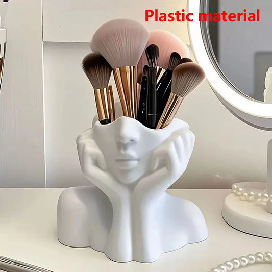 White human-face makeup brush holder with upright brush bristles in the cup