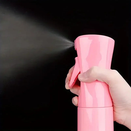 Pink hair spray bottle held in hand, with nozzle for hair misting