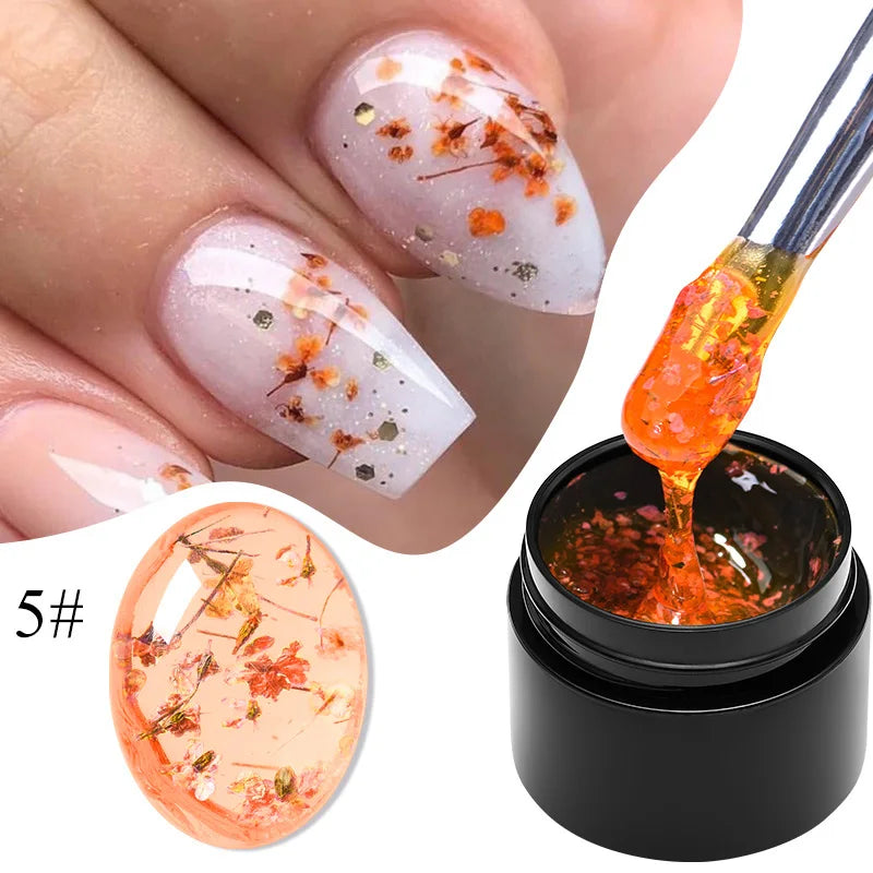 Clear orange gel nail polish with gold dried flower flecks on nails and gel bottle