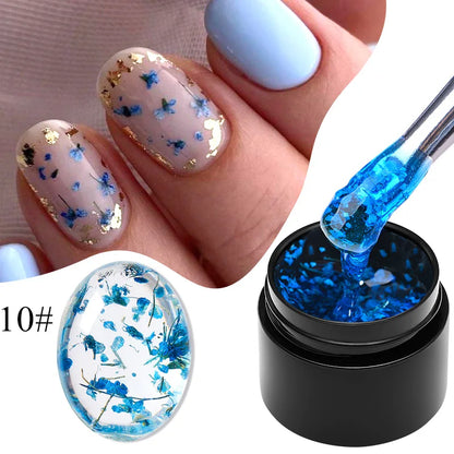 Light blue gel nail polish with blue dried flowers on nails and gel bottle