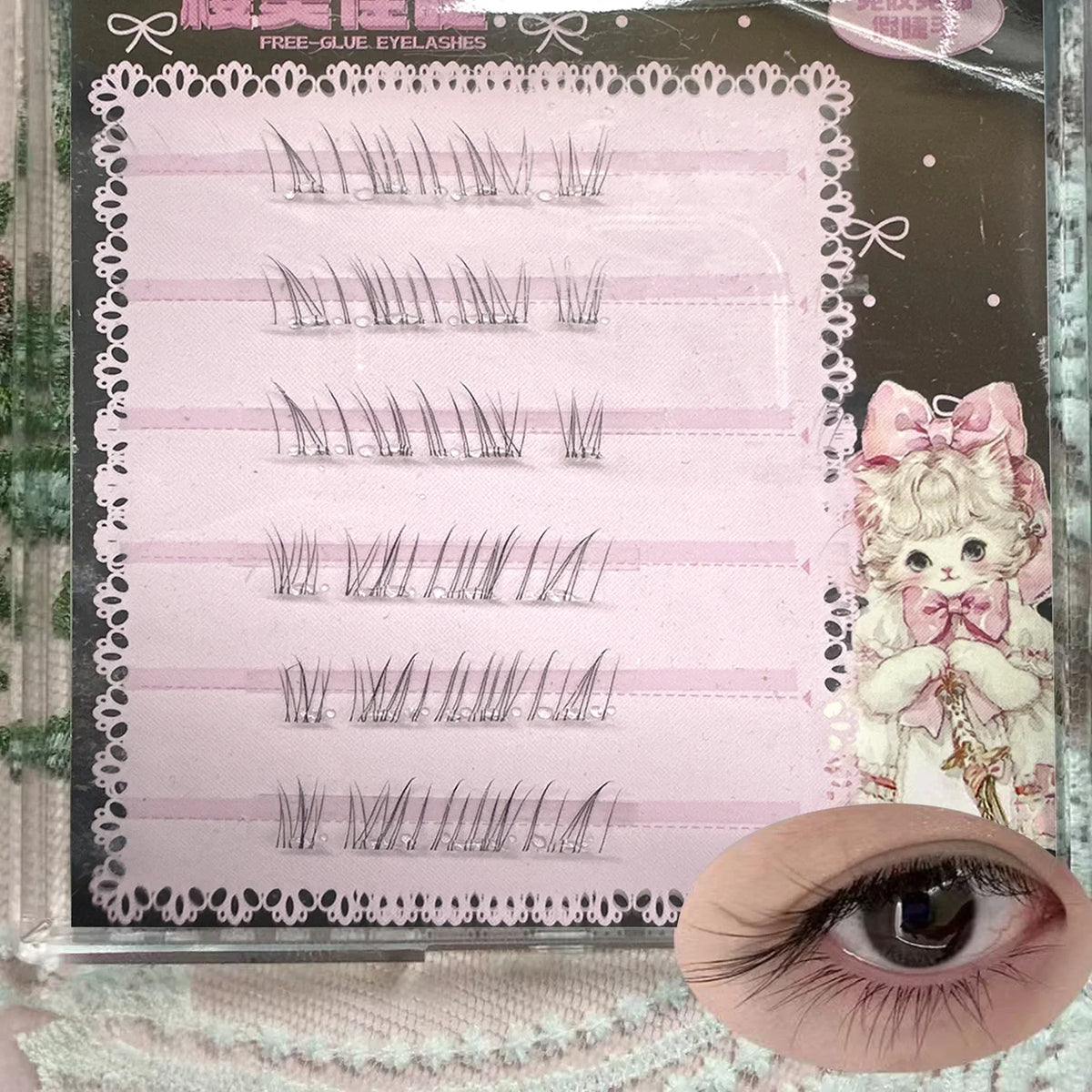 False eyelash clusters on a pink card with lace border and a printed cat design