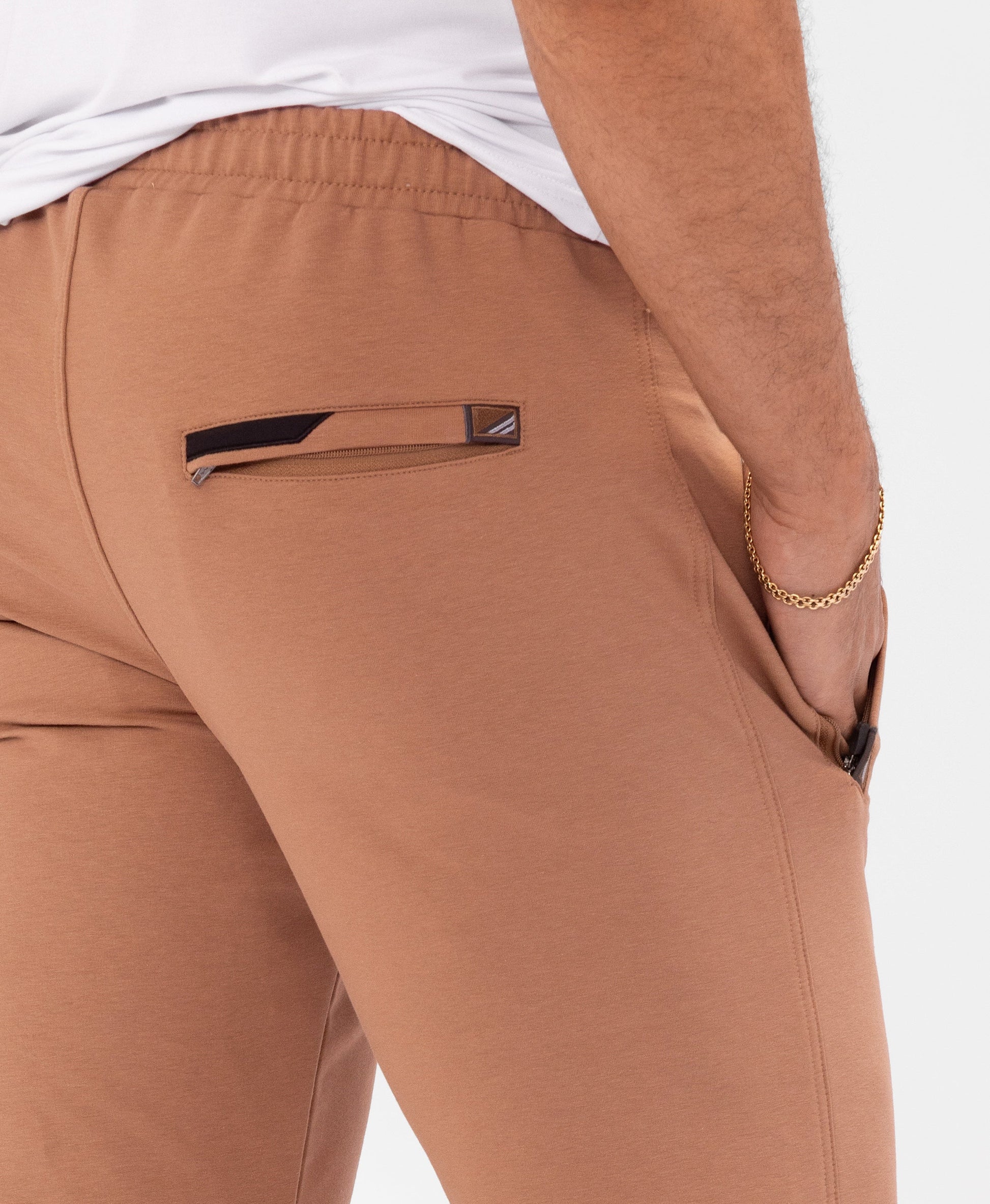 Rust-brown tapered athletic sweatpants detail with drawstring waistband and side pocket