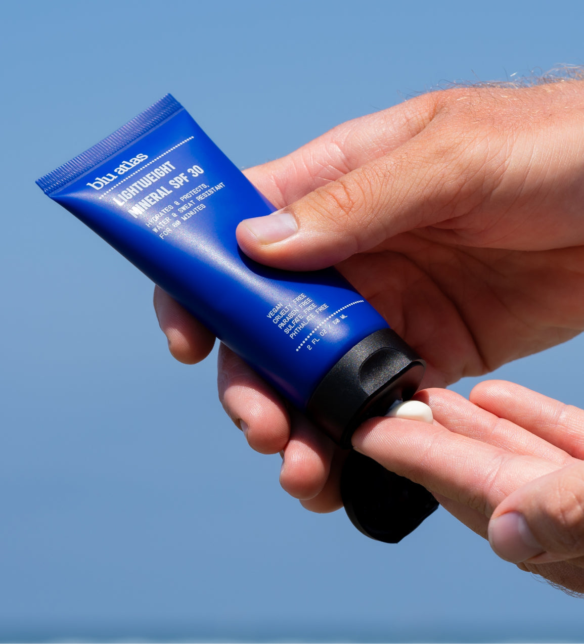 Lightweight mineral SPF 30 sunscreen tube being squeezed, hands with cream