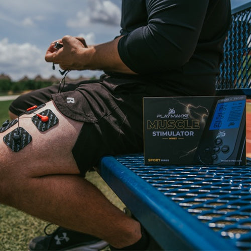 Muscle stimulator pads on leg with control unit and product box beside it