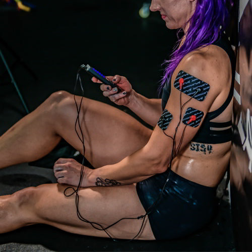 EMS/TENS muscle stimulator pads on leg with controller and cables in use
