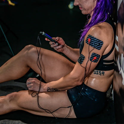 EMS/TENS muscle stimulator pads on leg with controller and cables in use