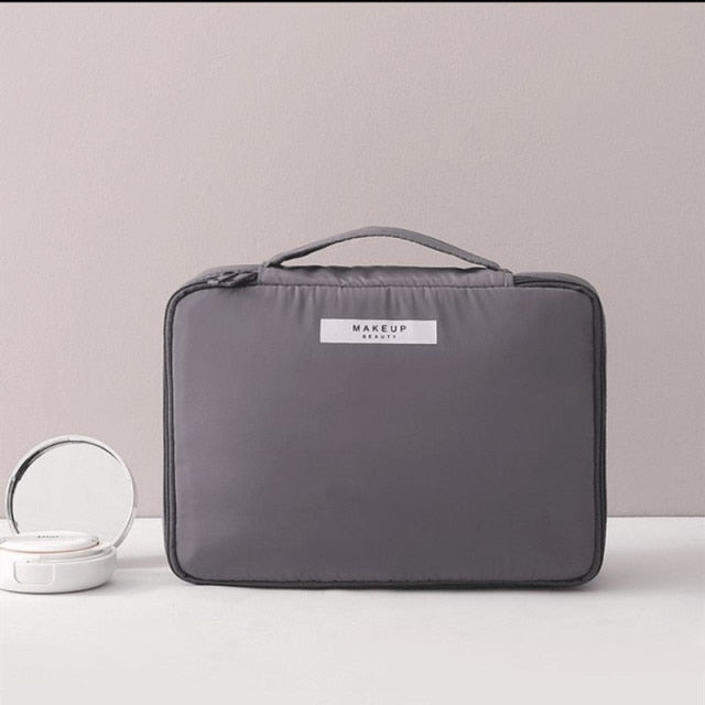 Gray cosmetic bag with top handle and front label patch