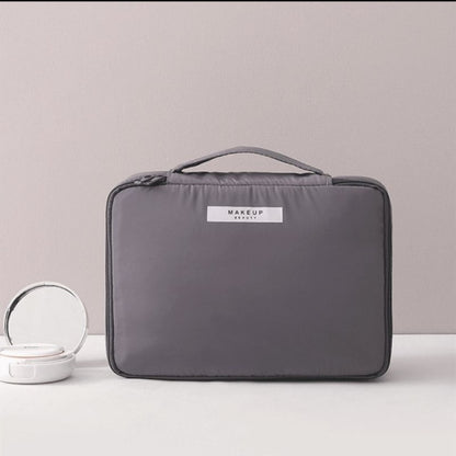 Gray cosmetic bag with top handle and front label patch
