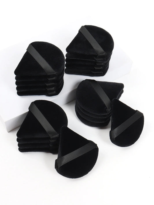 Black triangle velvet makeup puffs with gray bands, stacked in a cluster