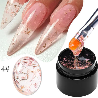 Flower fairy gel nail polish on nude pink nails with brown dried flower flakes; jar shown