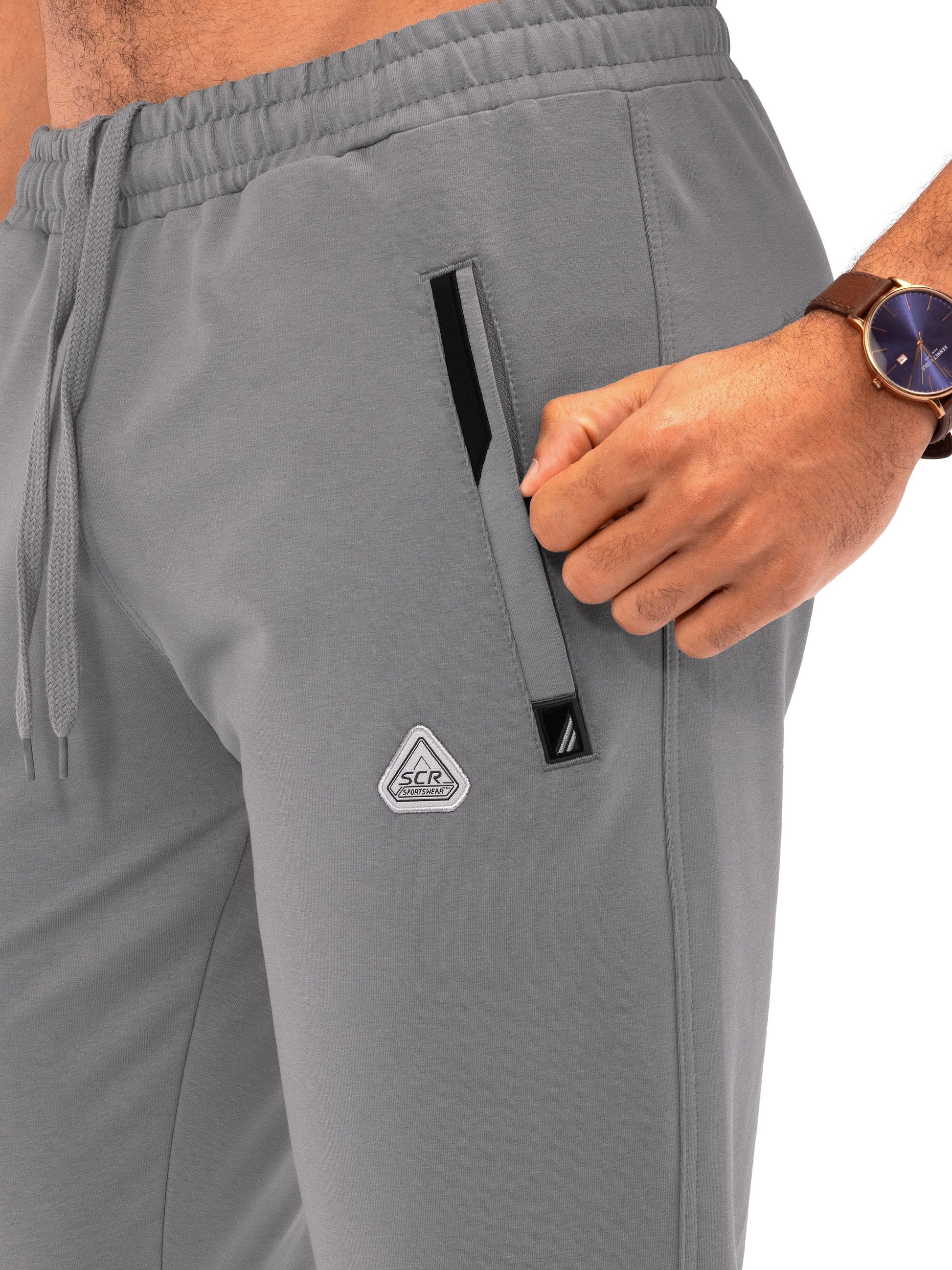 Dark grey athletic sweatpants detail with elastic waistband, drawstring, and side logo tab