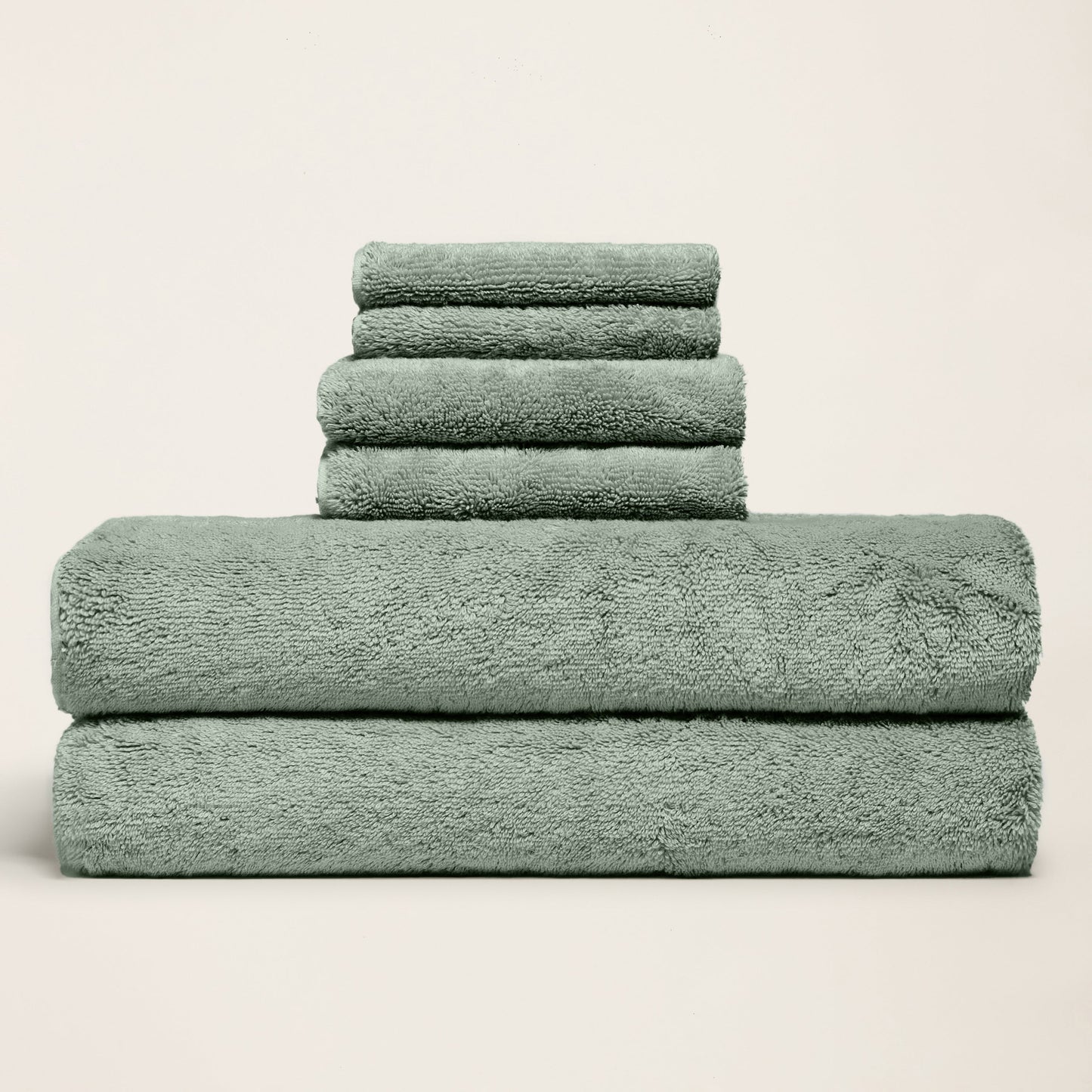 Dark green plush towels stacked and folded, thick terry texture