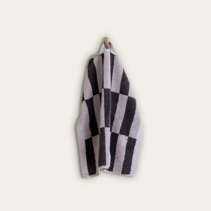 Lilac and charcoal checkered cotton towel, folded and hanging