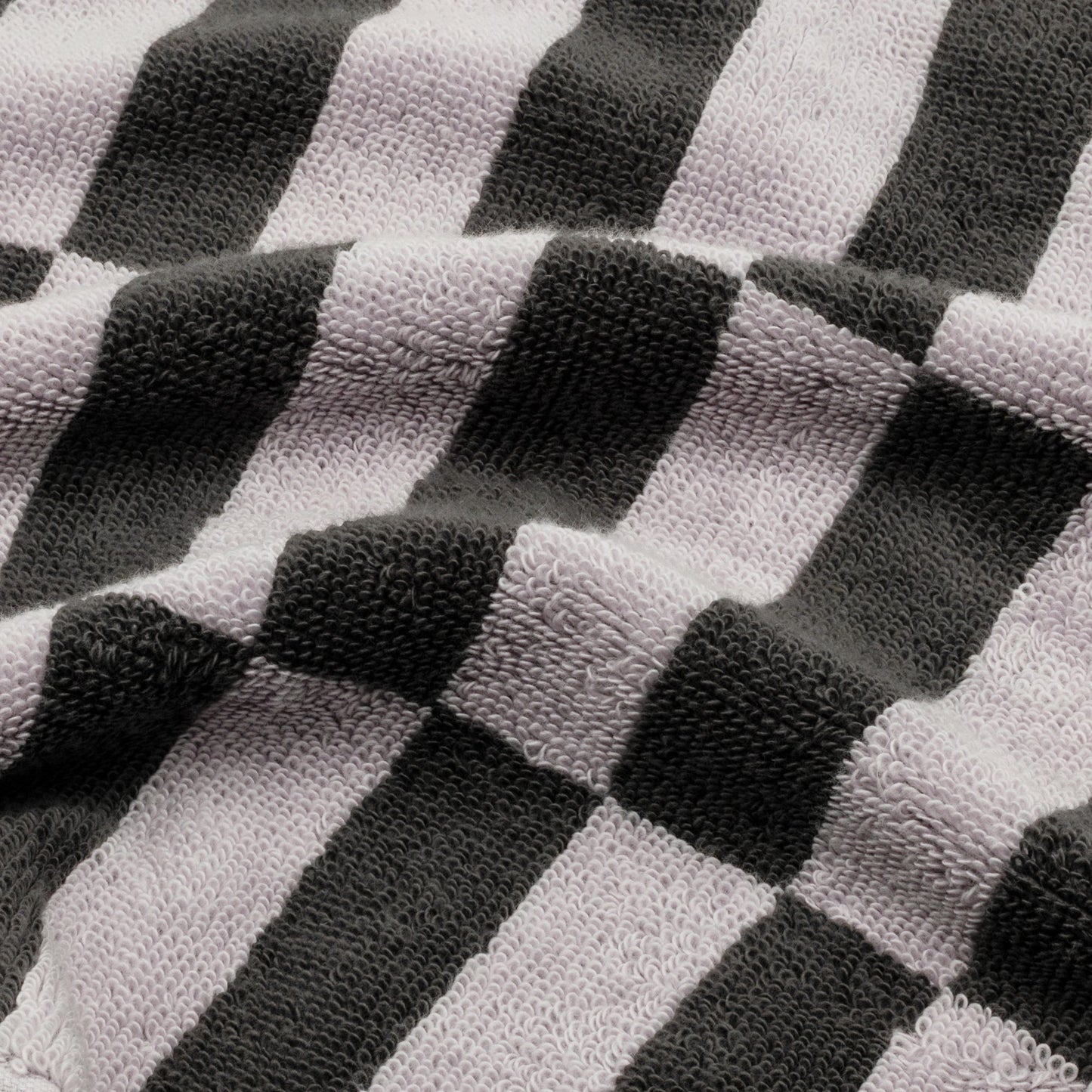 Close-up cotton towel fabric with lilac, light gray, and dark charcoal checker stripes