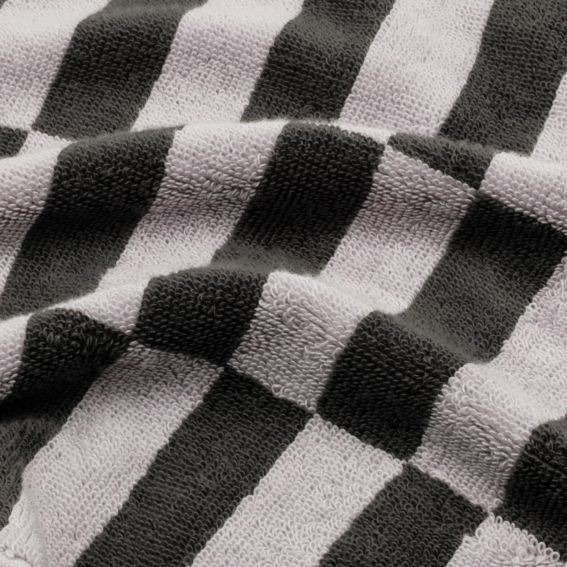 Close-up cotton towel fabric with lilac, light gray, and dark charcoal checker stripes