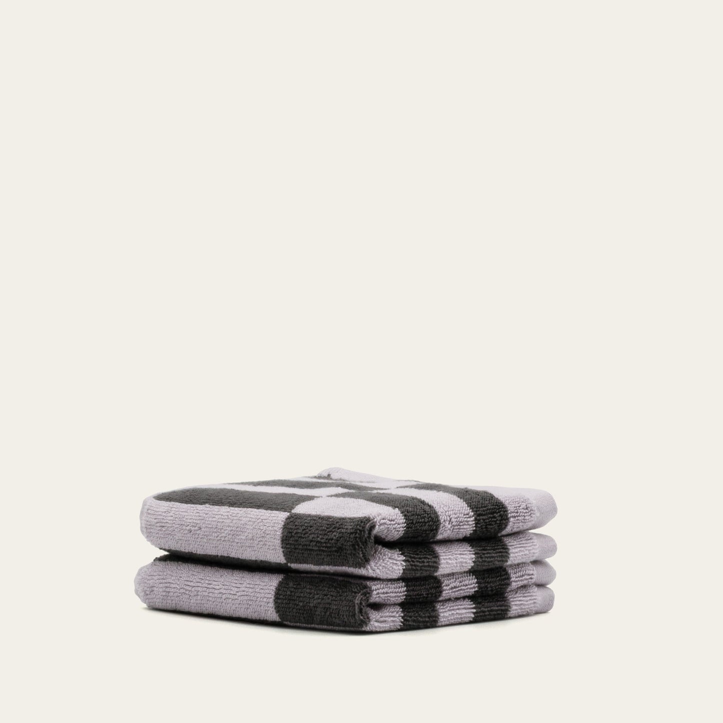 Rolled cotton towels in lilac and charcoal with black-and-lilac checker stripe pattern