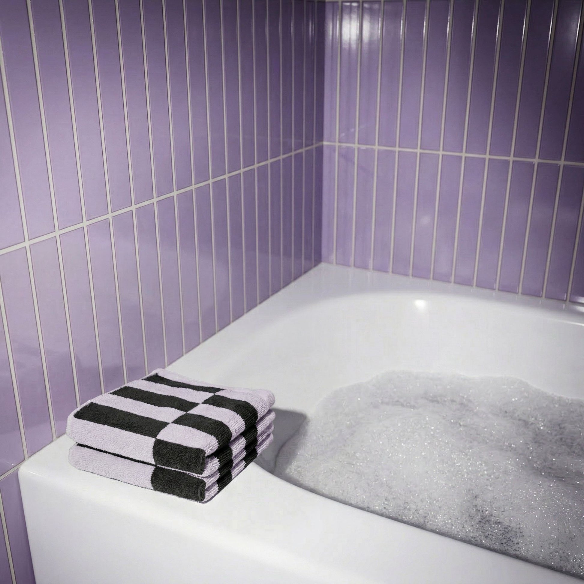 Folded cotton towel in lilac and charcoal with black-and-lilac checker stripe bands
