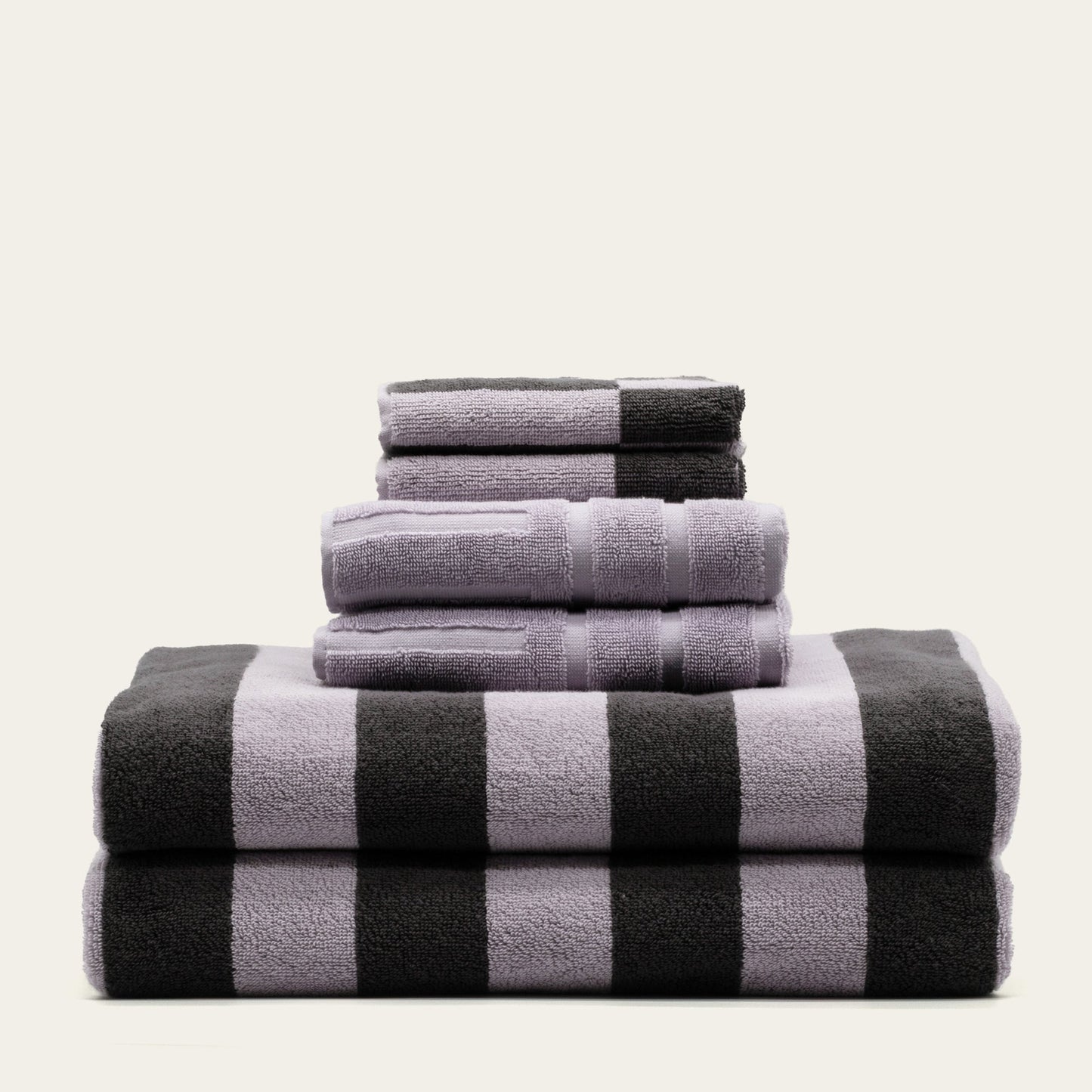 Stack of cotton towels in lilac and charcoal, black-and-lilac checker stripe pattern